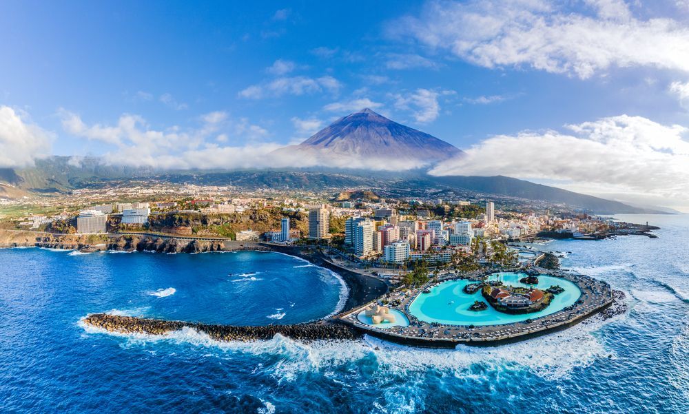 Coastal city with volcanic mountain backdrop, blue ocean, and a lagoon.