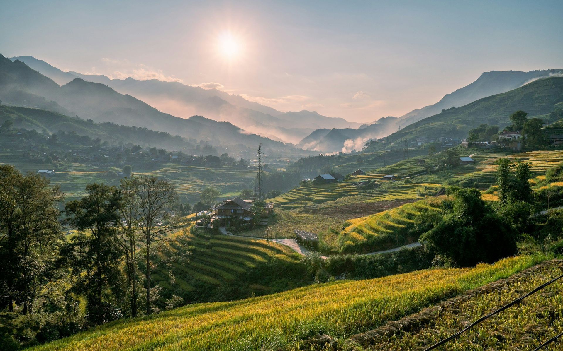 Rolling green hills and valleys, bathed in sunlight. Mountains in the distance, hazy.