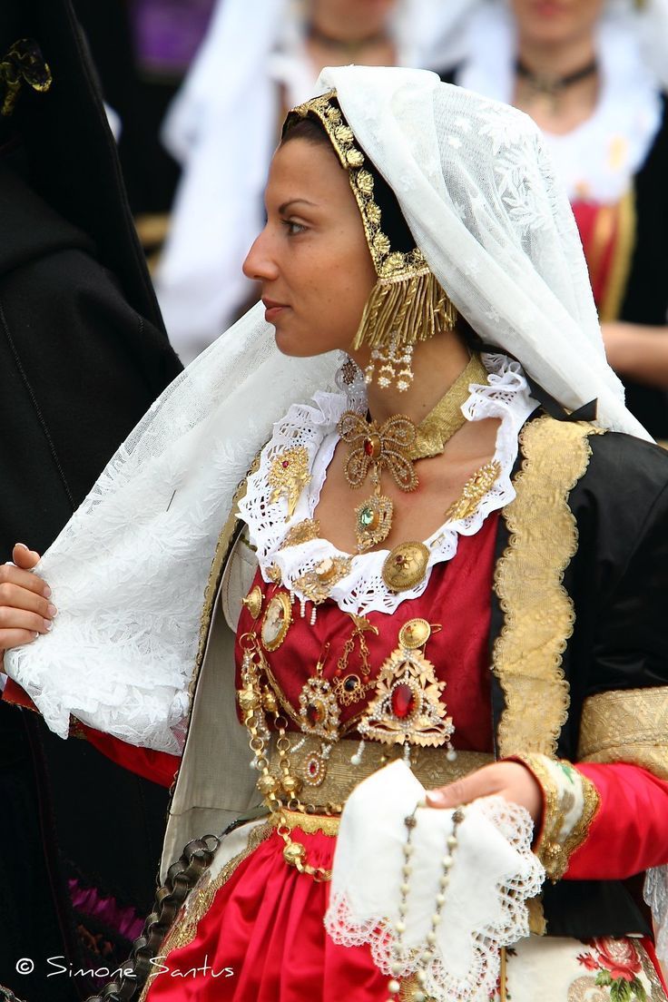 Una donna con un abito rosso e oro con un velo bianco in testa