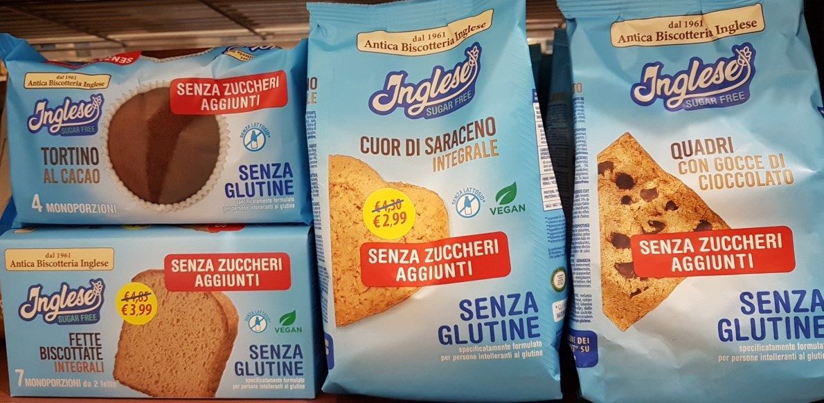 Quattro confezioni di prodotti da forno senza glutine a marchio Inglese. Le confezioni sono azzurre con etichette rosse.