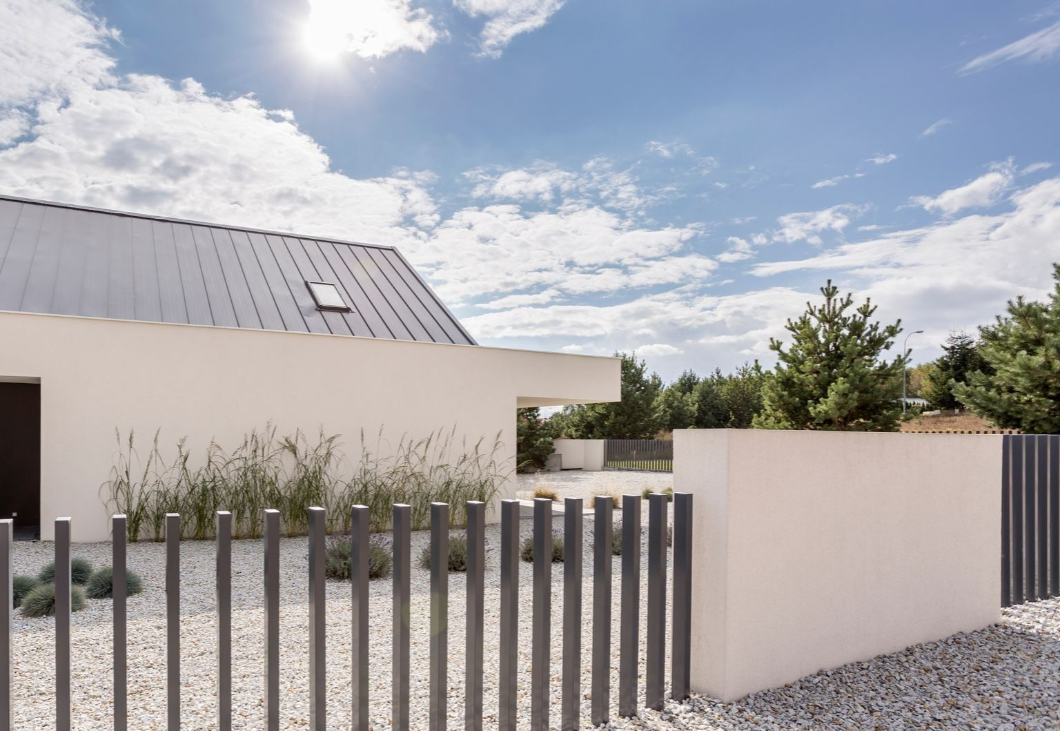 A white house with a metal roof and a fence in front of it.