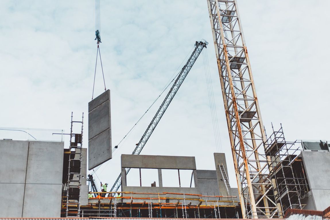 A construction site with a crane lifting a piece of concrete.