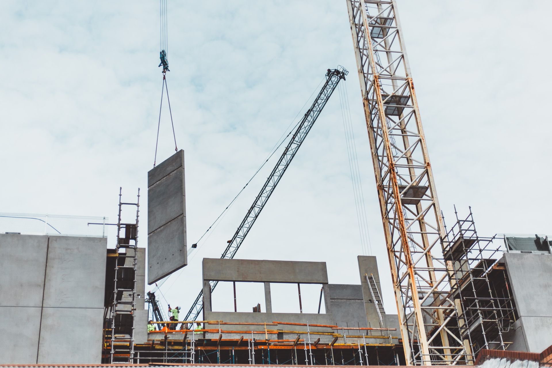 A construction site with a crane lifting a piece of concrete.
