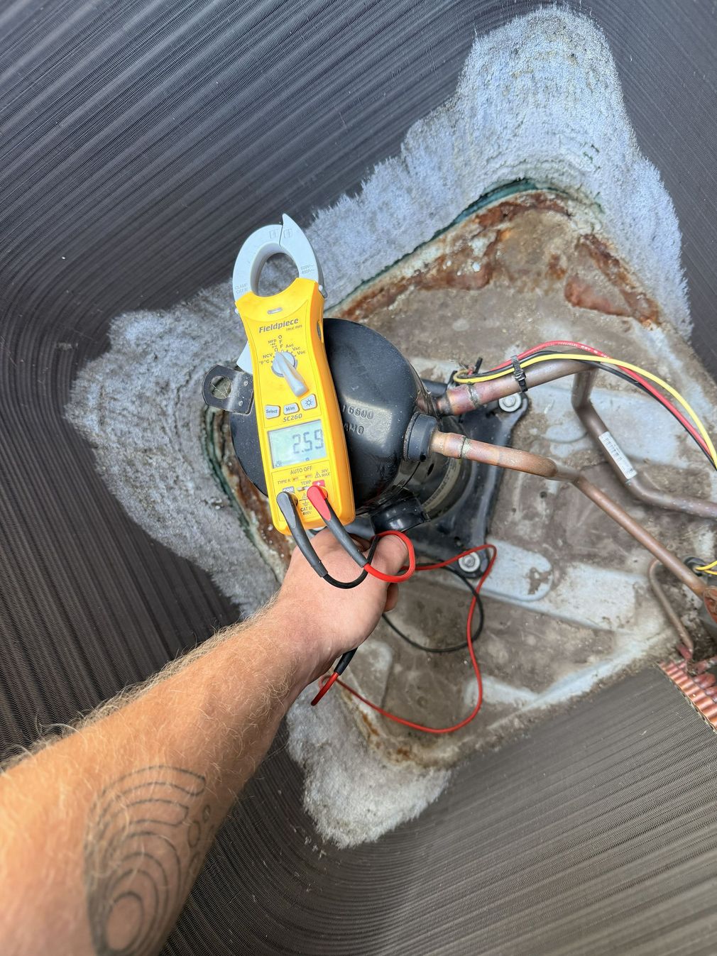 Technician checking HVAC unit with gauges inside an open cabinet