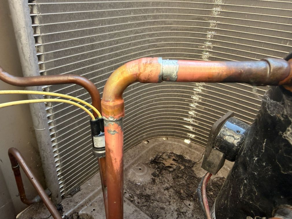 Two large HVAC units installed indoors on a wall with insulated ductwork and metal piping.