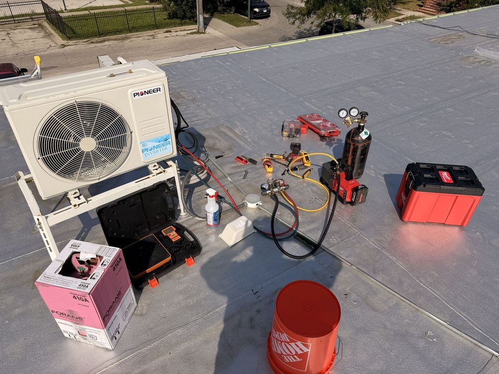 Technician using gauges to service an outdoor HVAC unit with gloves and tools