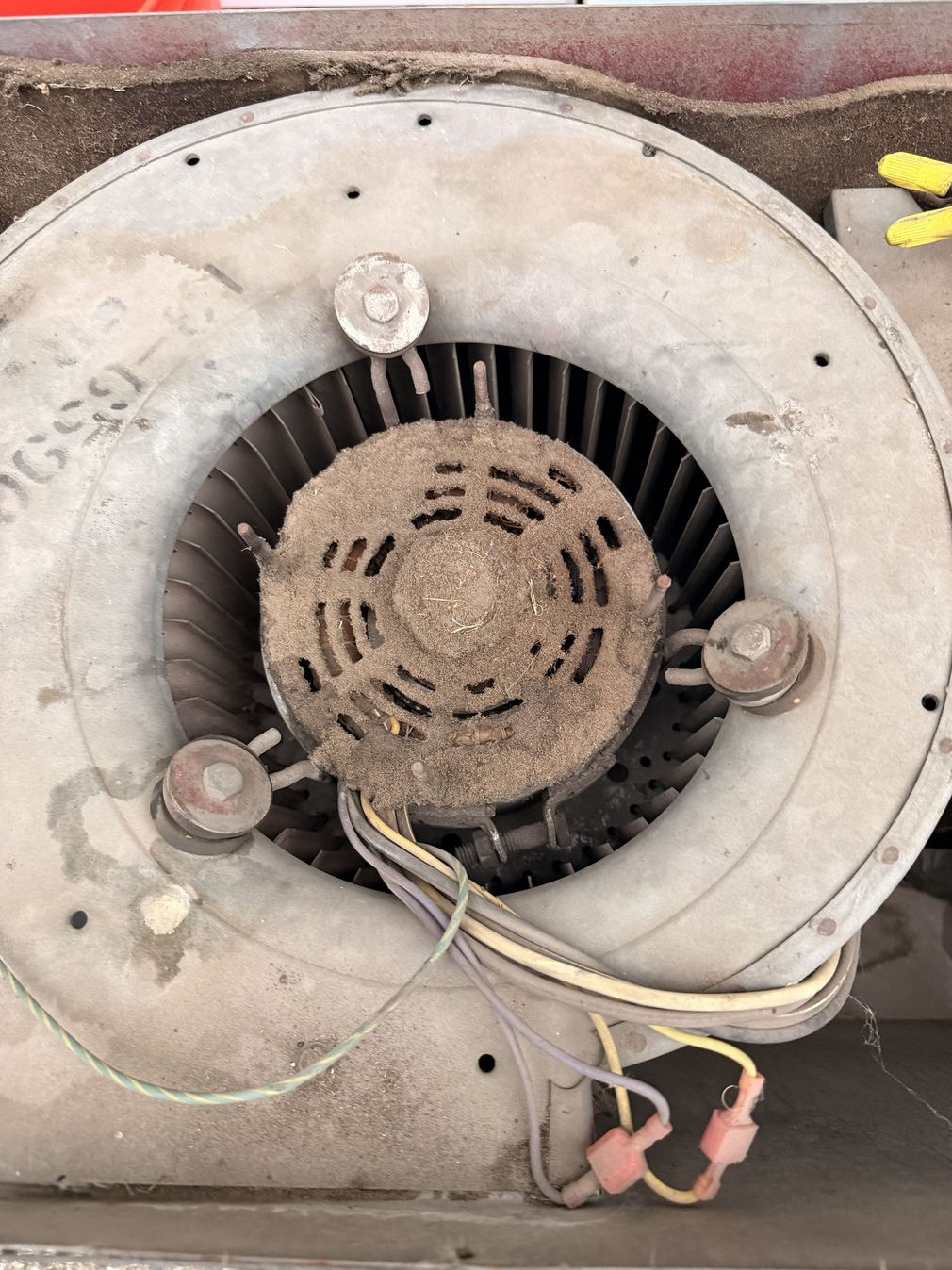Technician kneels beside a house-mounted HVAC unit on a brick driveway, using tools and gauges.