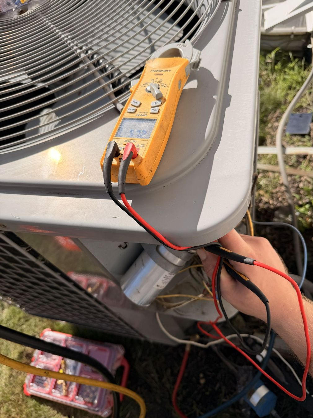 HVAC technician servicing an outdoor air conditioner unit beside a suburban house
