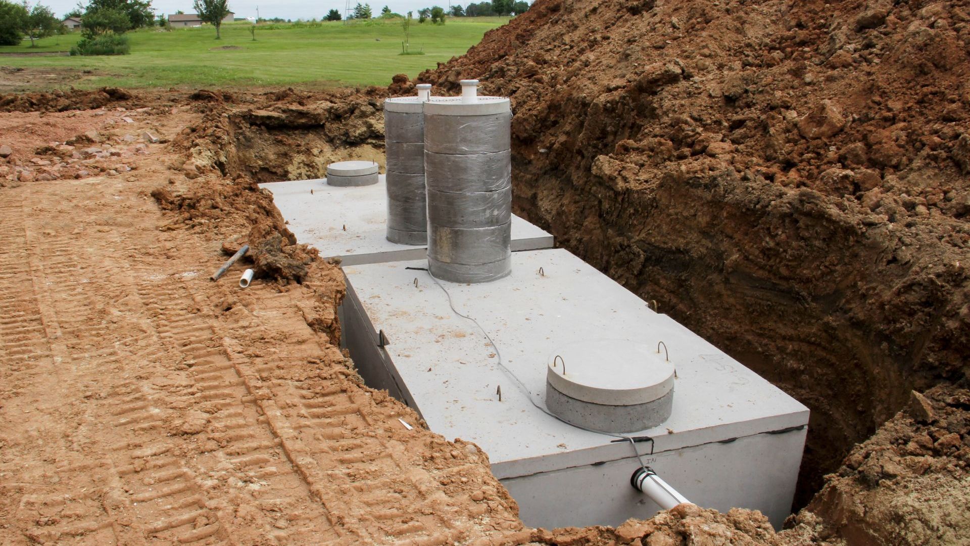 A septic tank is sitting in the dirt next to a pile of dirt