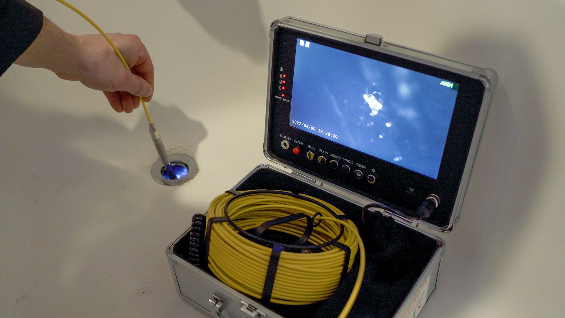A person is holding a hose in front of a drain camera