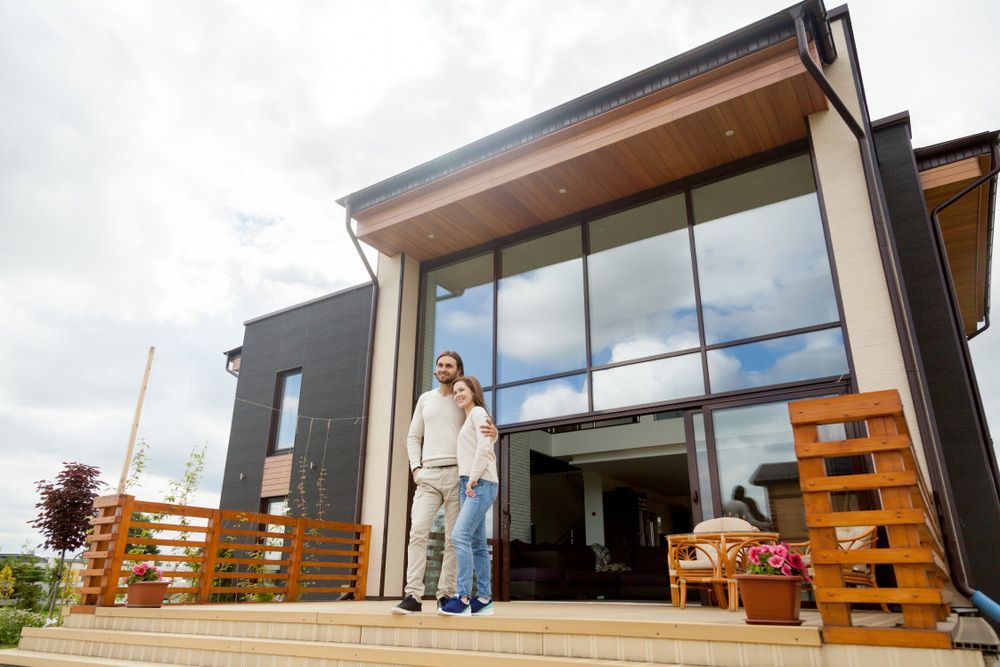 A Man And A Woman Are Standing In Front Of A Large House — Glenn Merrick Constructions In Bowen, QLD