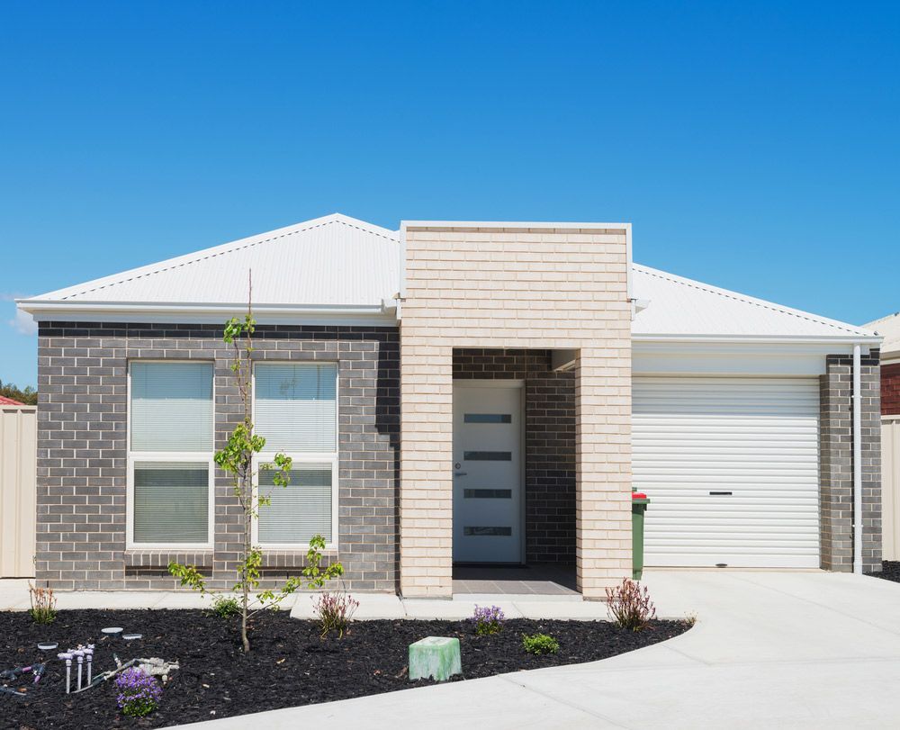 A Brick House With A White Garage Door — Glenn Merrick Constructions In Bowen, QLD