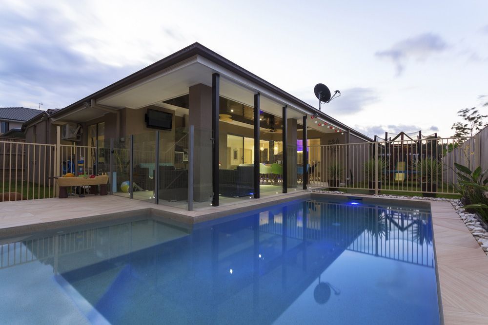 A Large Swimming Pool Is In The Backyard Of A House — Glenn Merrick Constructions In Collinsville, QLD