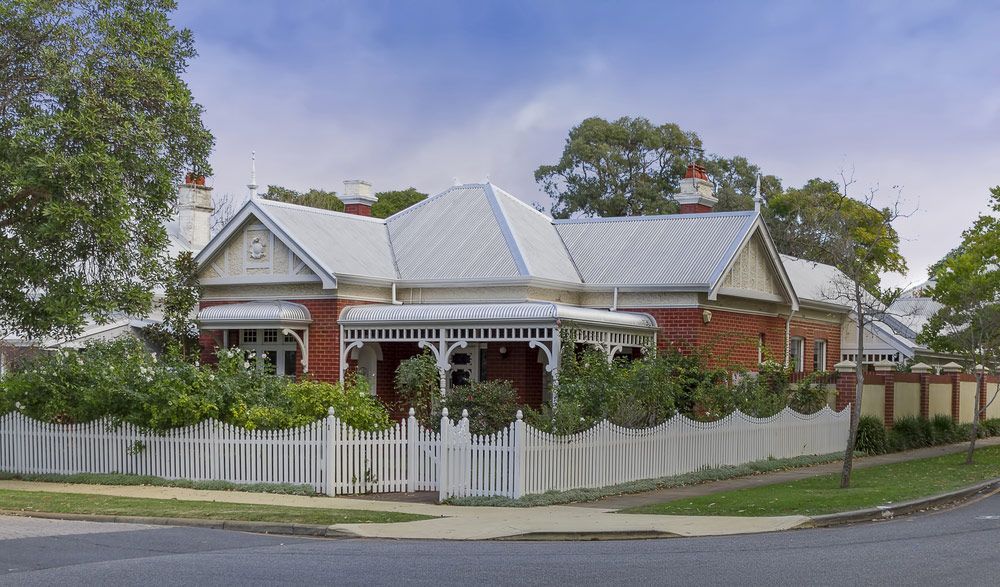 A Brick House With A White Picket Fence Around It — Glenn Merrick Constructions In Bowen, QLD