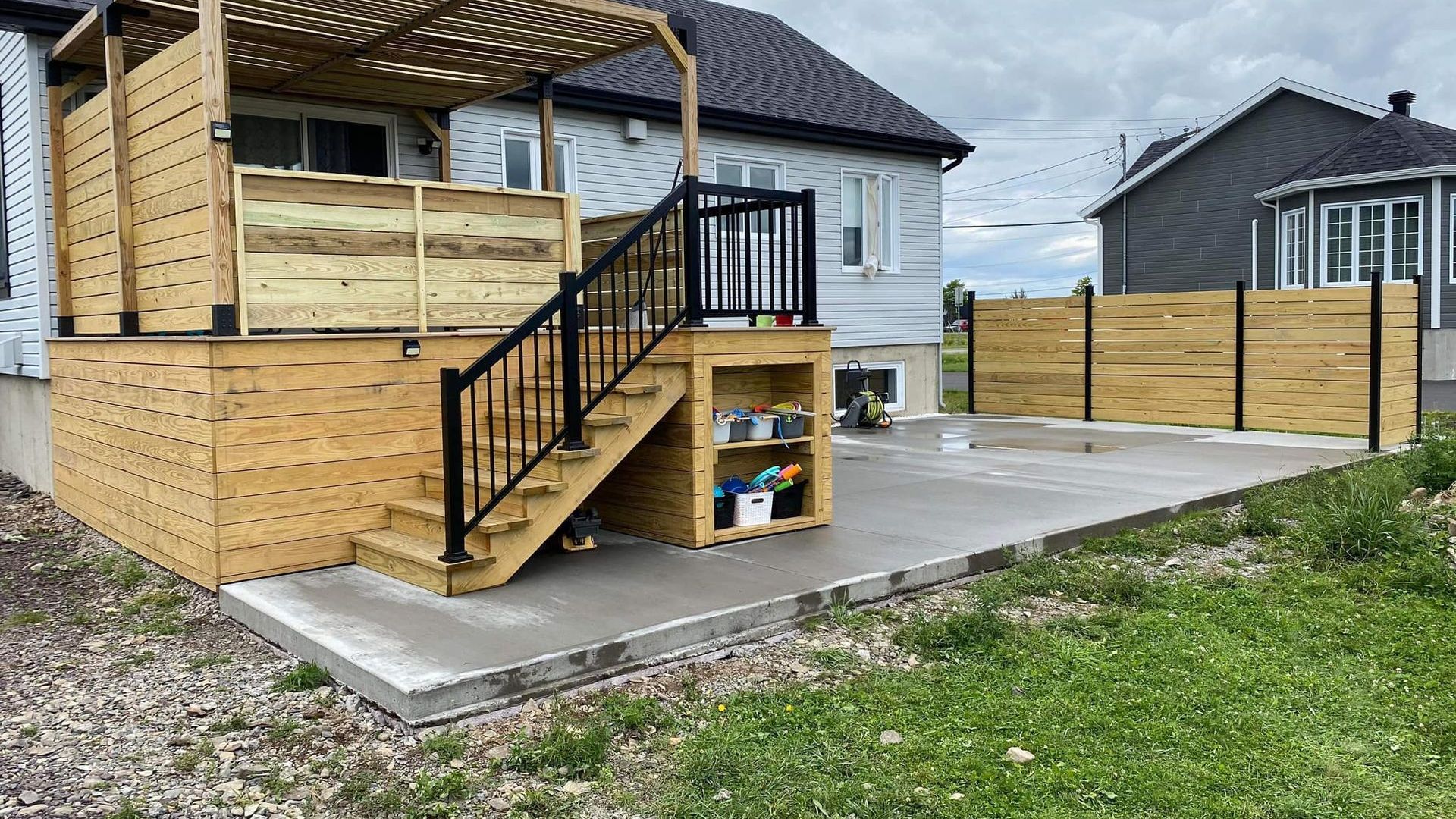 Une terrasse en bois avec des escaliers et une clôture devant une maison.