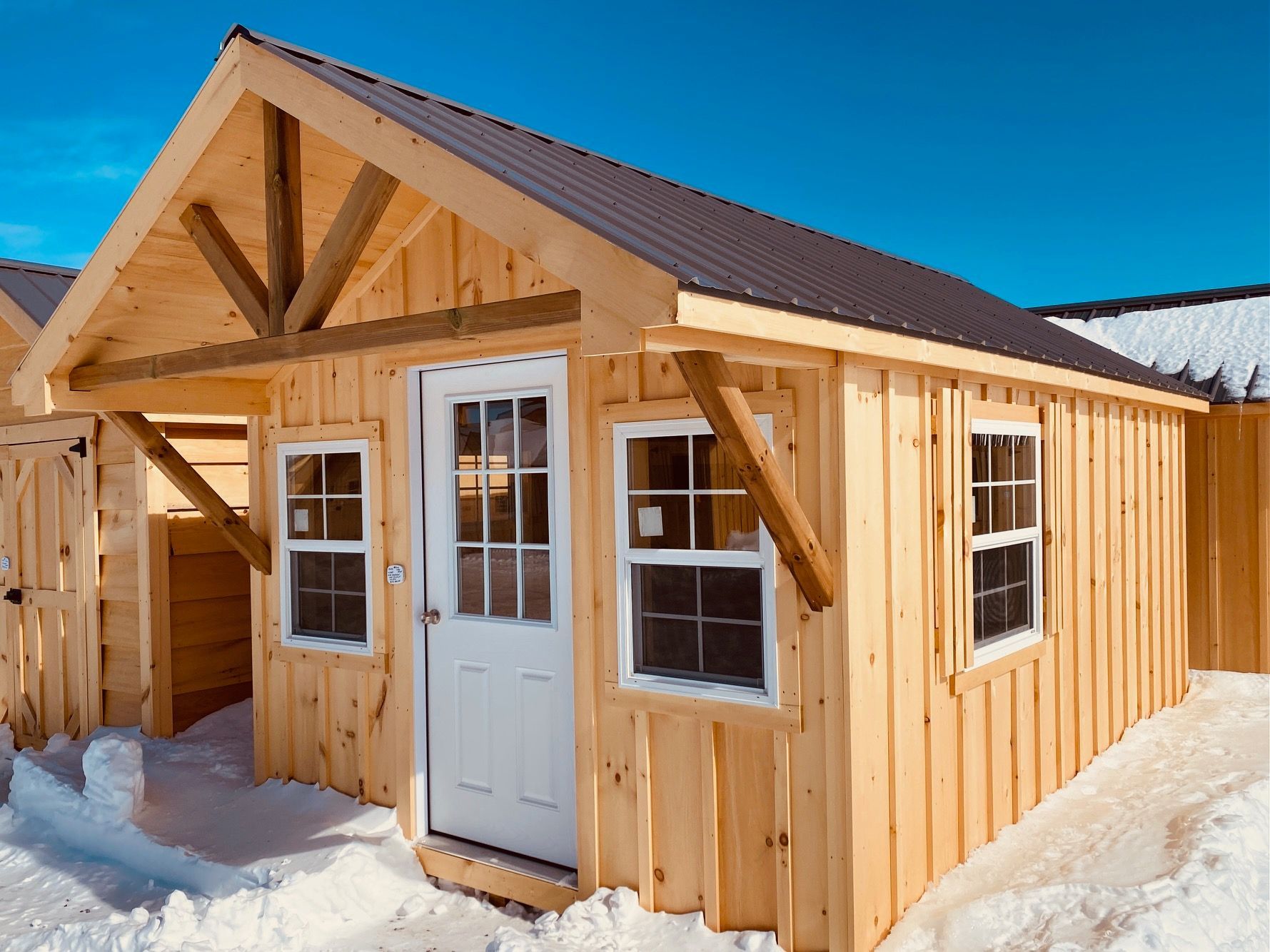 A small wooden shed with a brown roof is sitting in the snow.