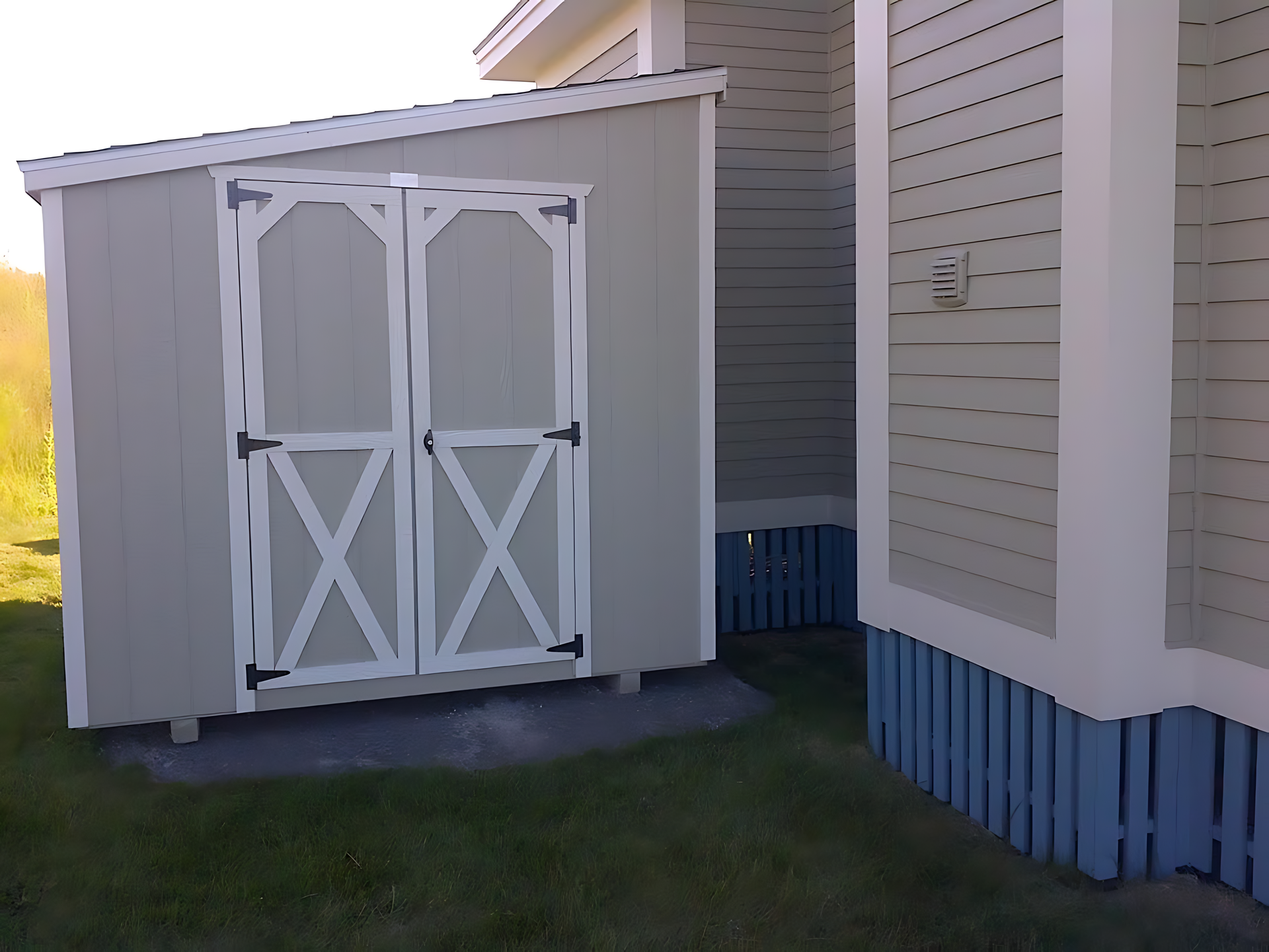 A shed with a x on the door is next to a house