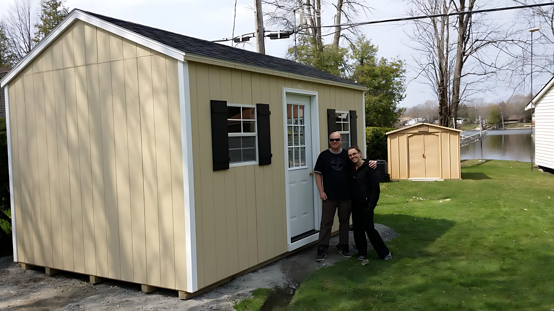 A man and a woman are standing in front of a shed.