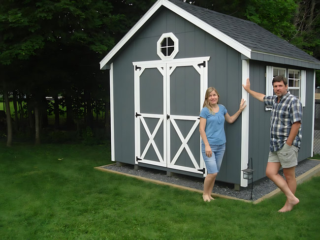 A man and a woman are standing in front of a shed