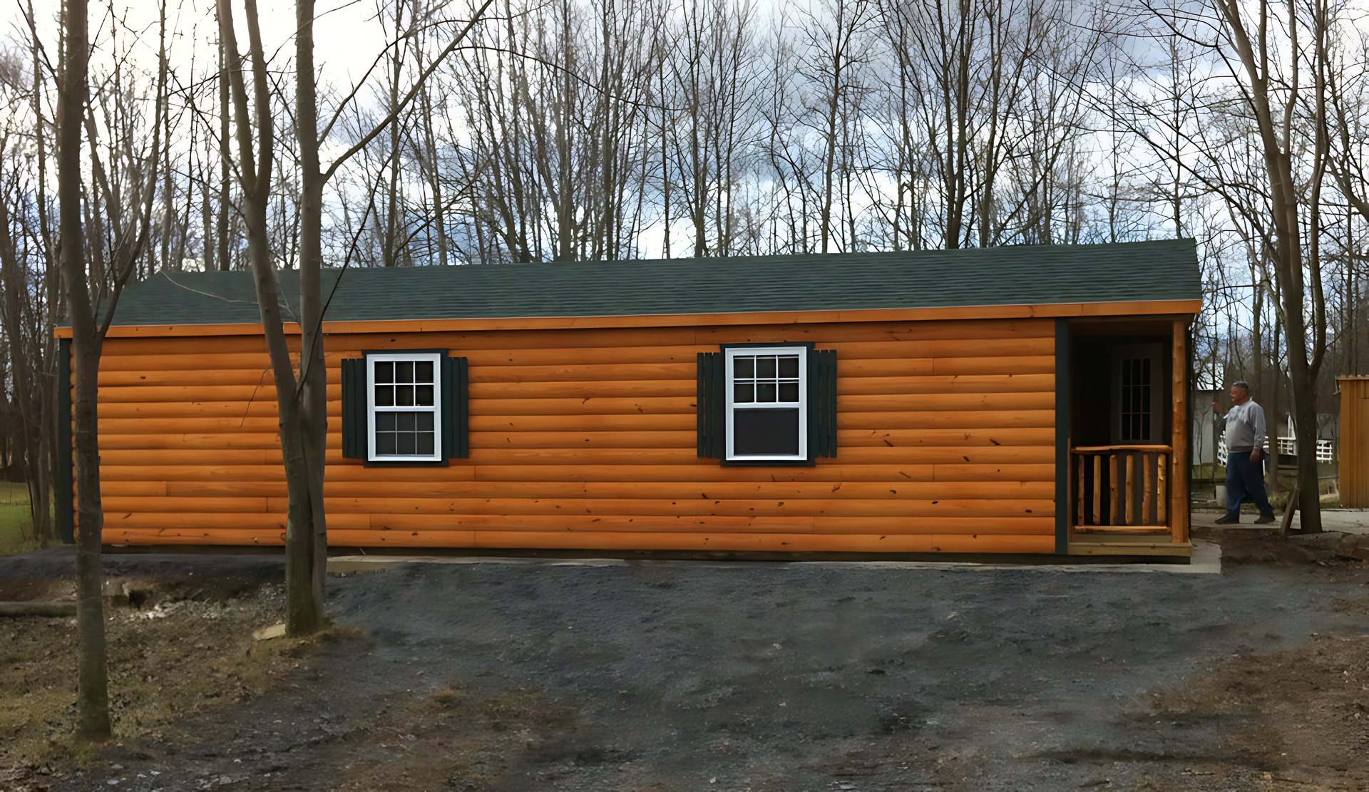 A log cabin with a green roof and black shutters