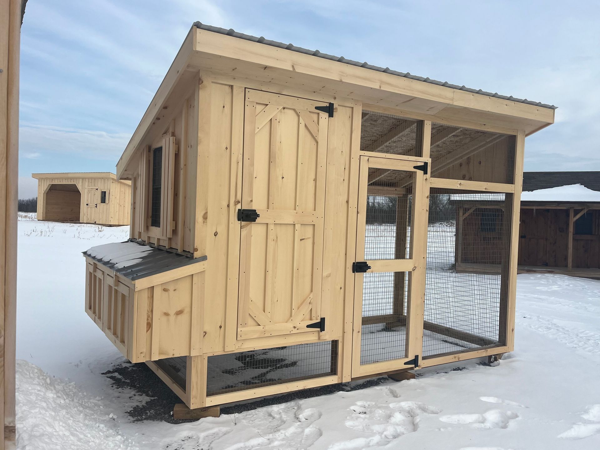 A wooden chicken coop is sitting in the snow.