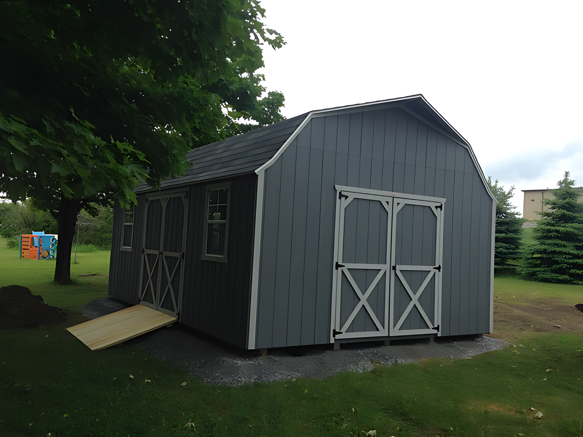 A gray barn with a ramp in front of it