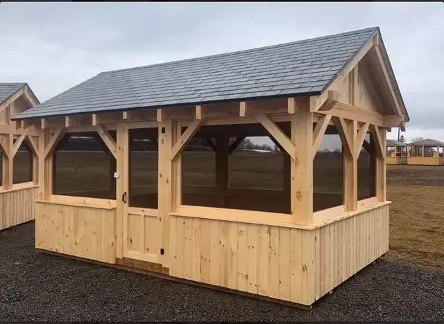 A wooden gazebo with a screened in porch and a slate roof