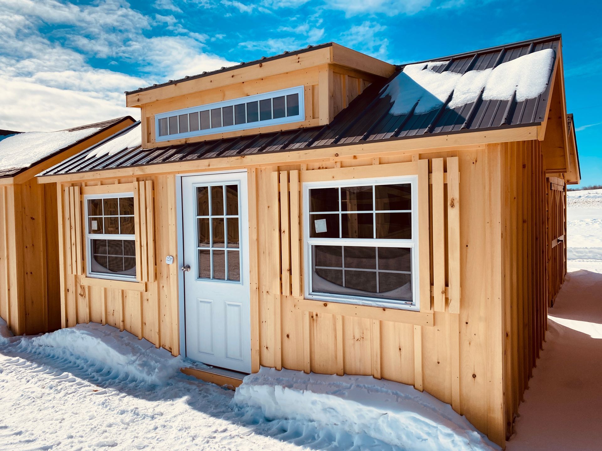 A small wooden house with a metal roof is sitting in the snow.