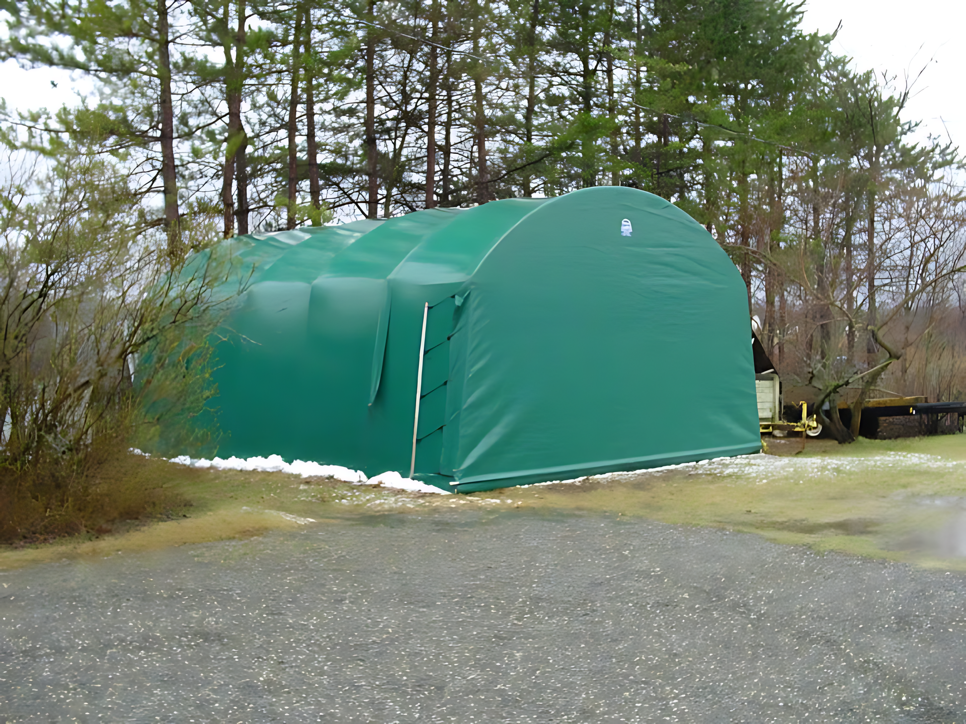A large green tent is sitting in the middle of a gravel road