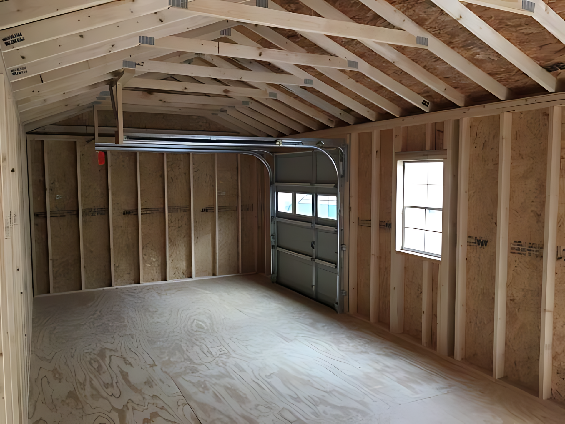 An empty garage with a garage door open and a window.
