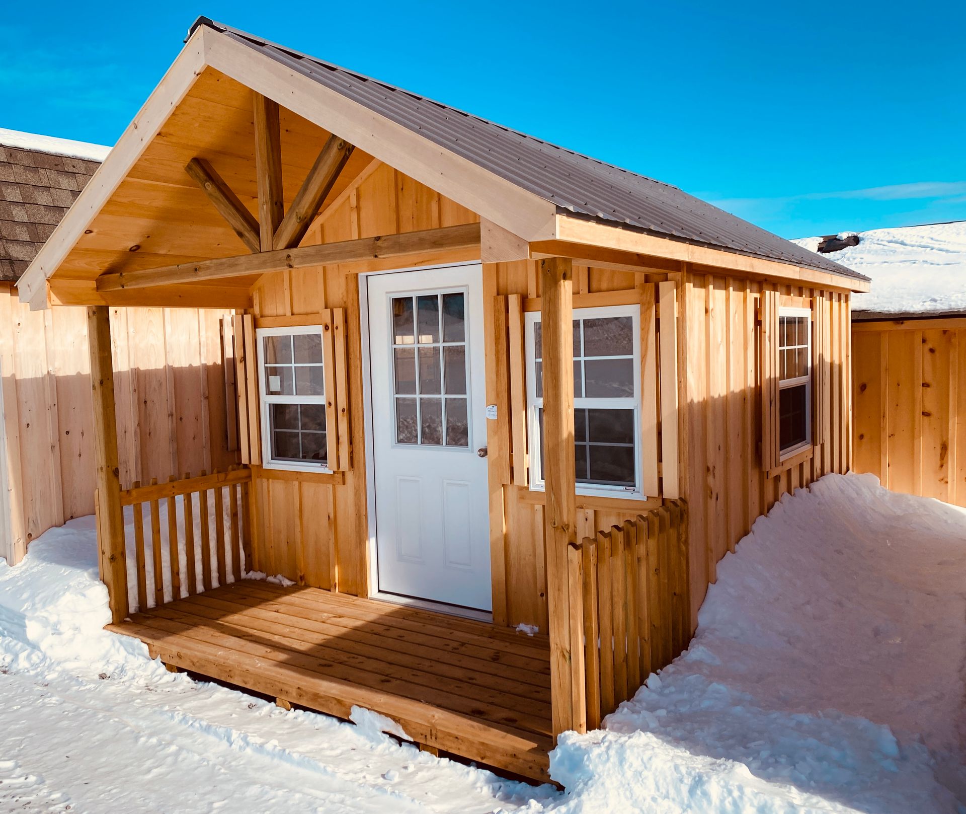 A small wooden house with a porch in the snow