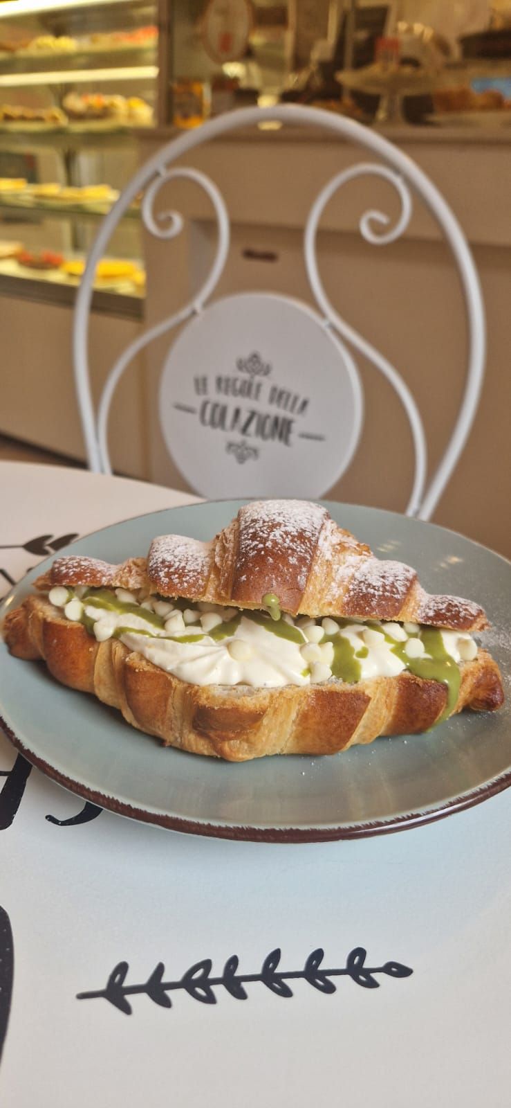 Cornetti ricoperti di cioccolato, noci e frutti di bosco esposti su uno scaffale di vetro.