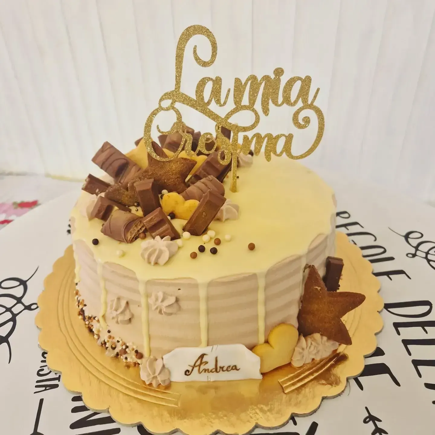 Torta decorata con cioccolato Kinder e una decorazione dorata con la scritta 