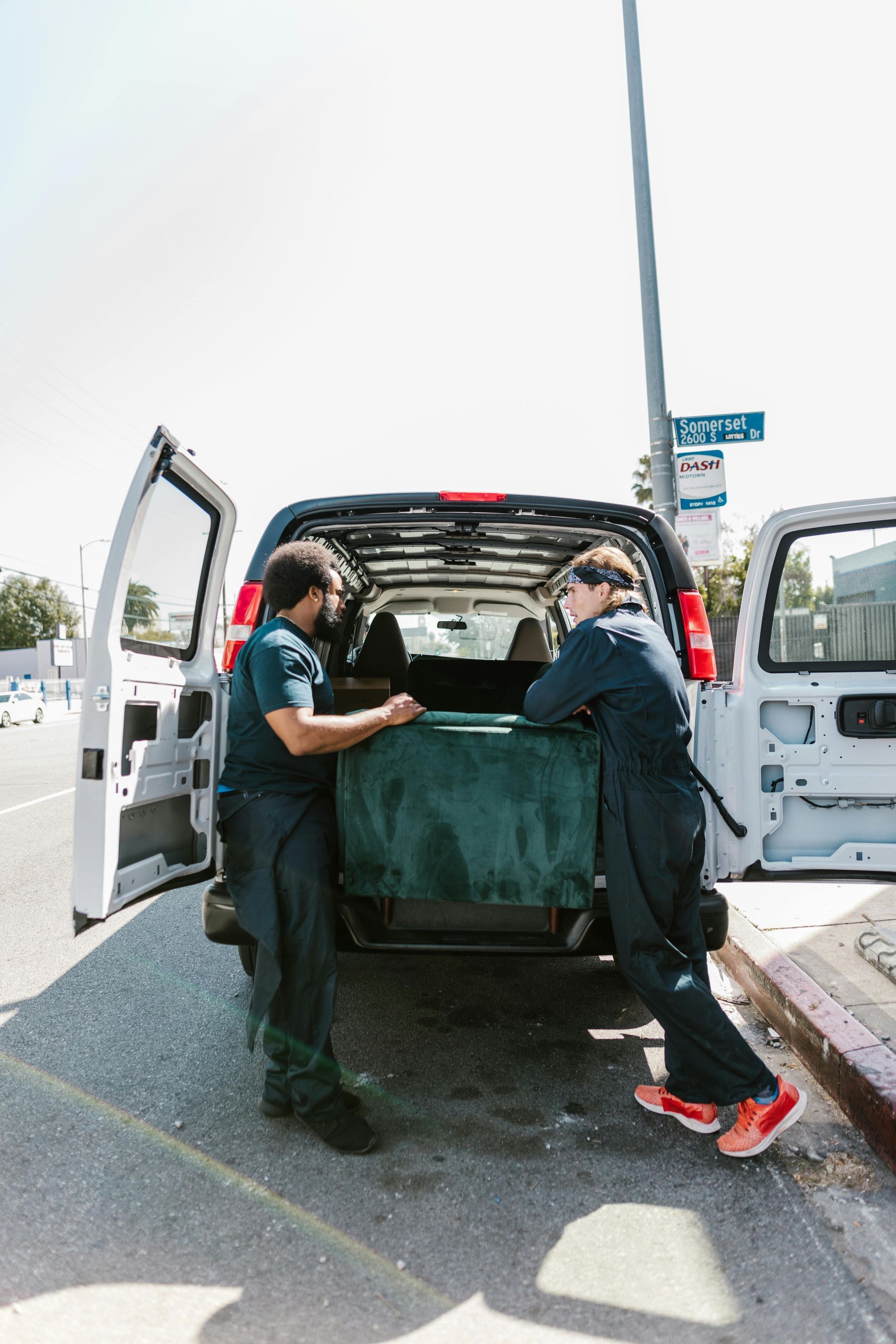 Two movers loading a green blanket into the back of a van.