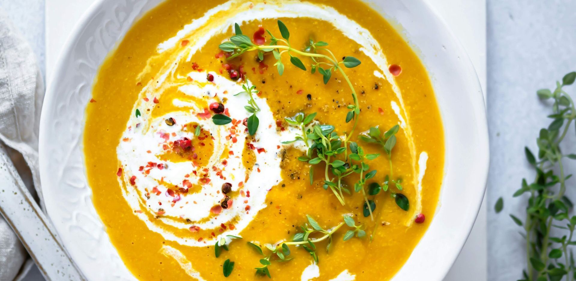 Nourishing postpartum soup topped with a swirl of cream and fresh microgreens.