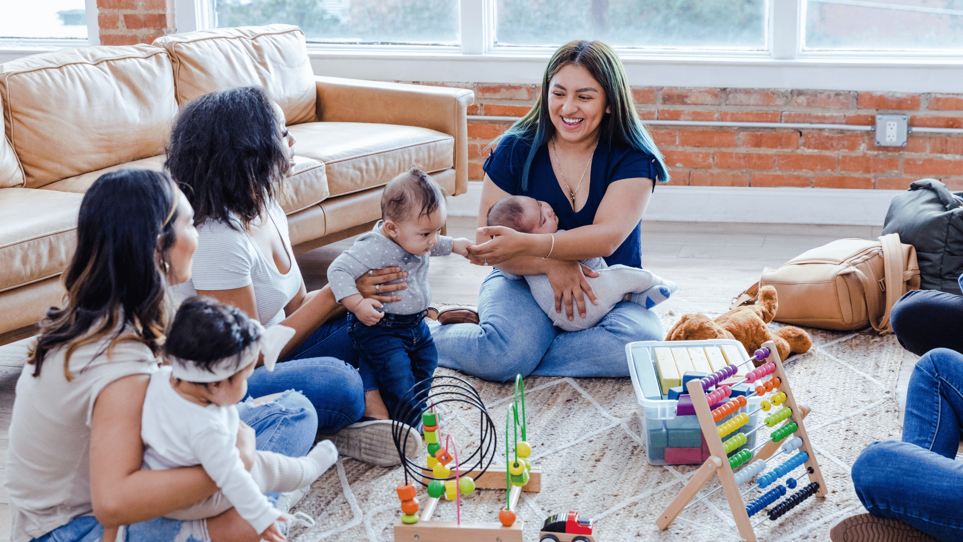 A group of women sitting on the floor, engaging with a baby in a warm and friendly atmosphere.