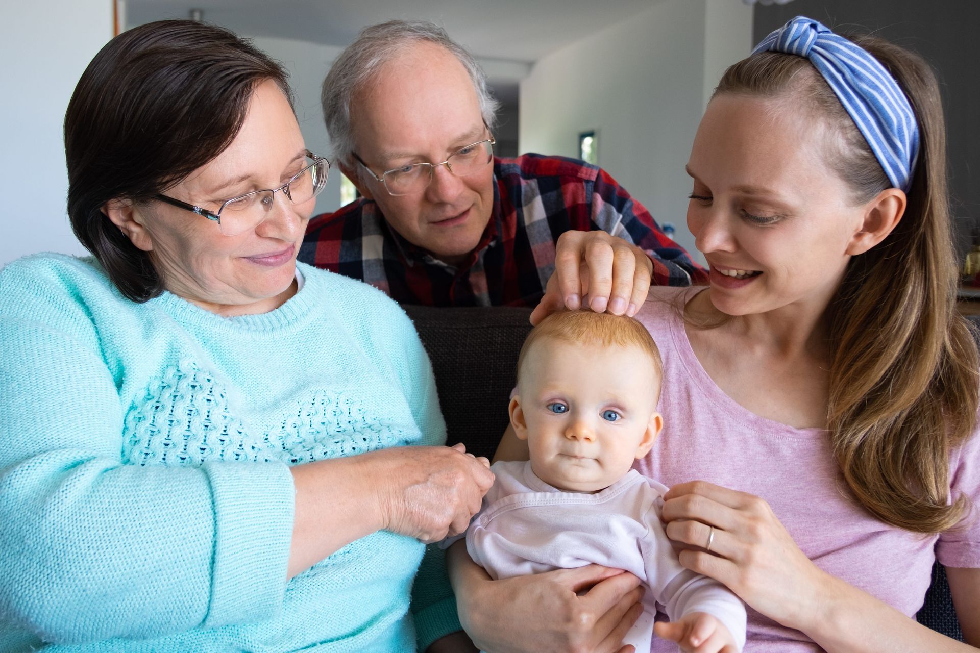 An older couple smiles at a young baby, creating a warm and loving family moment.