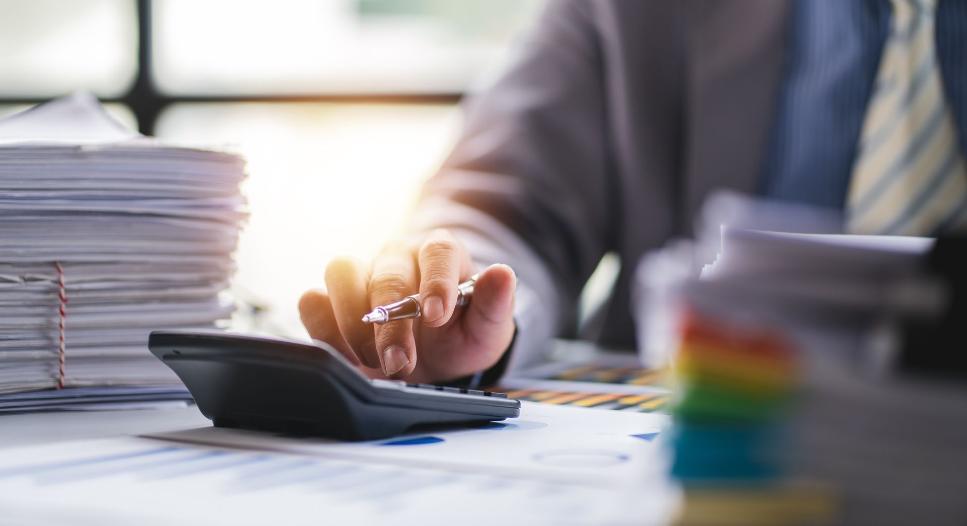 CPA using a calculator to review business tax documents for a business owner