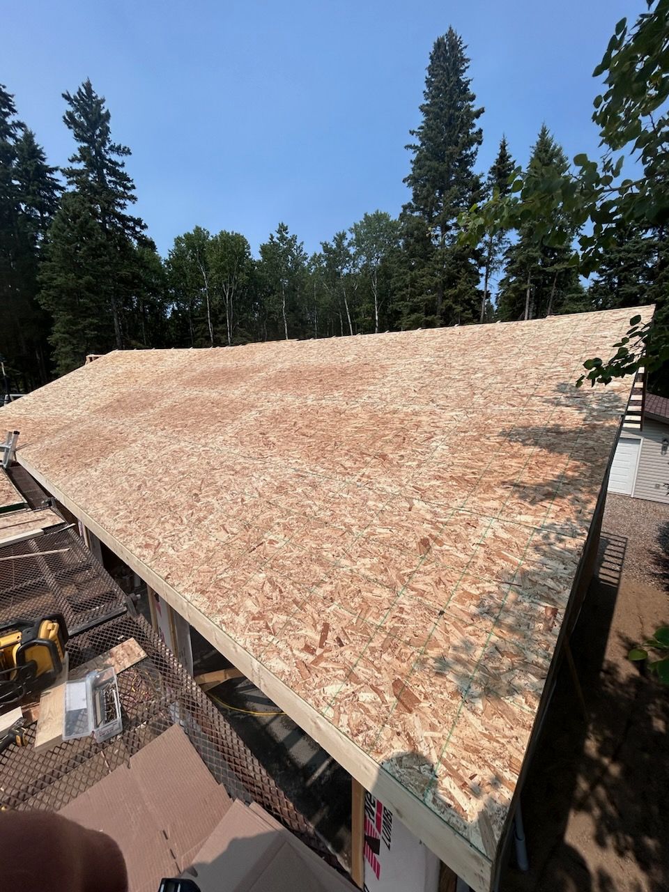 New roof under construction; OSB sheathing covers the roof of a house, bright sunny day.