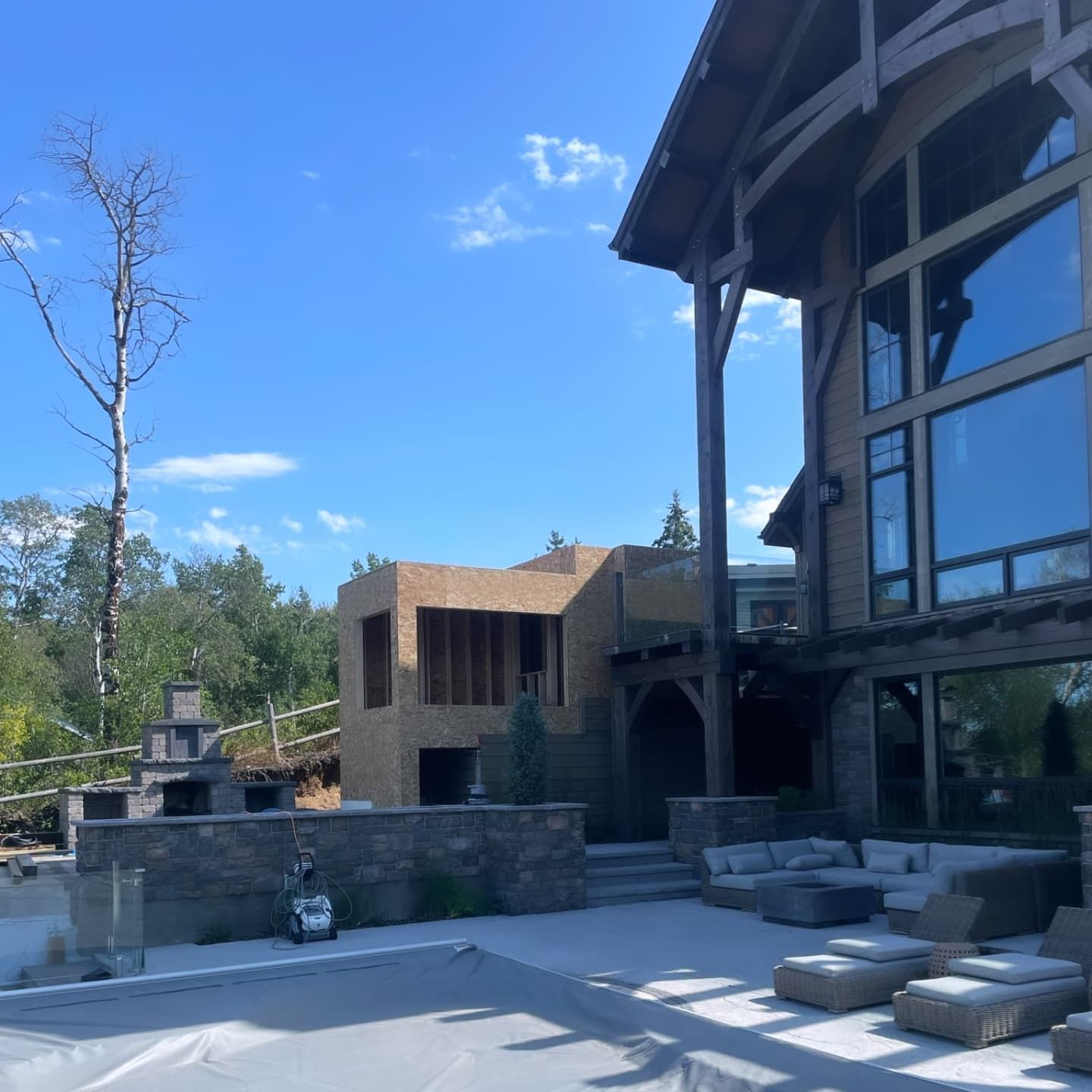 Luxury home exterior with pool, construction, and blue sky.