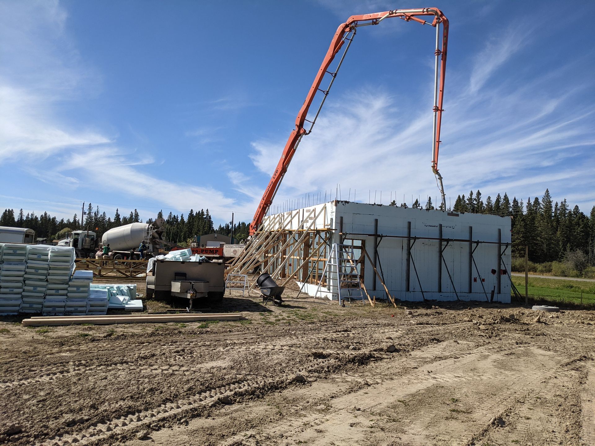 Concrete being poured into insulated concrete form walls at a construction site. Red pump arm and truck visible.