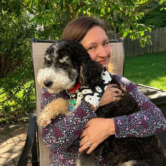 A Woman is Sitting in a Chair Holding a Small Dog