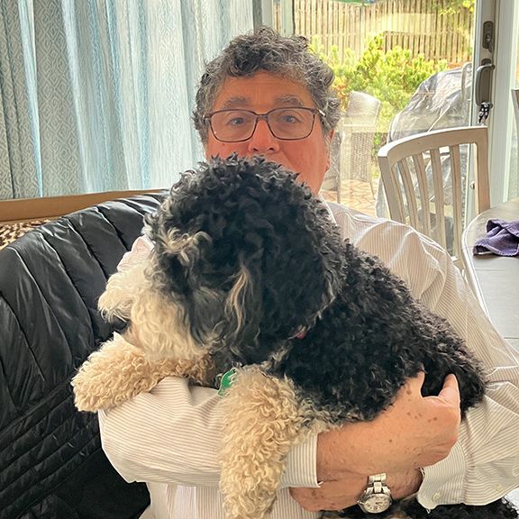 A Man is Holding a Small Black and White Dog in His Arms