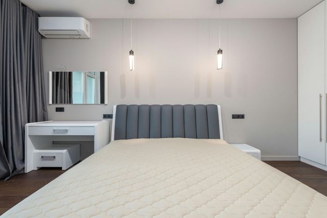 Modern bedroom with a bed, vanity, wall lights, air conditioner, and curtains