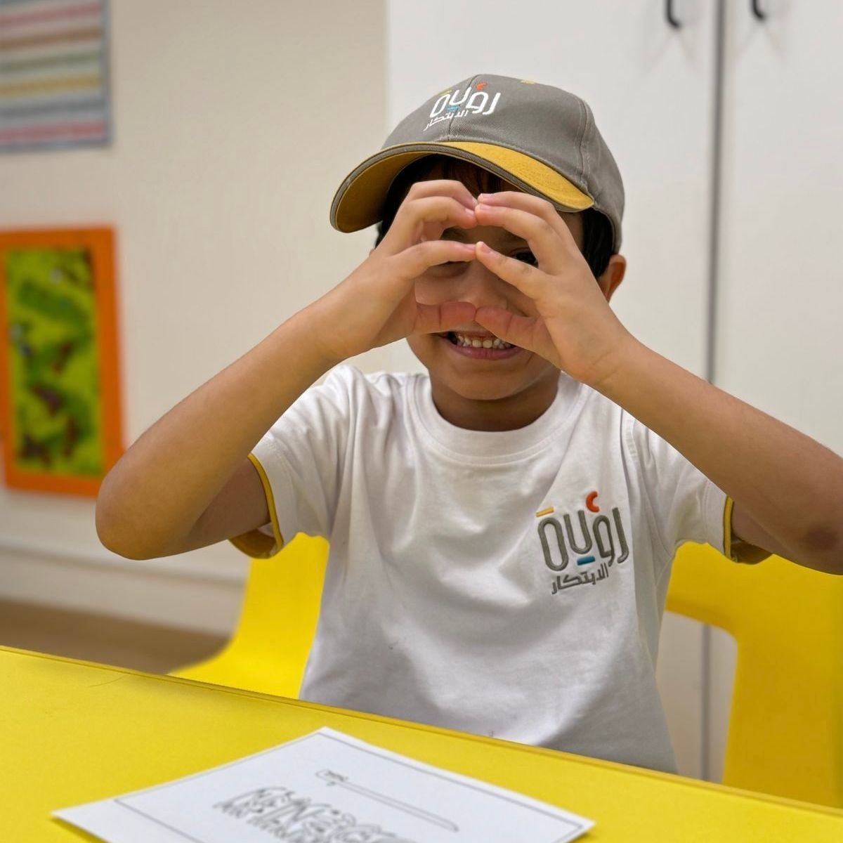 A young boy wearing a hat and a white t-shirt with the word oui on it