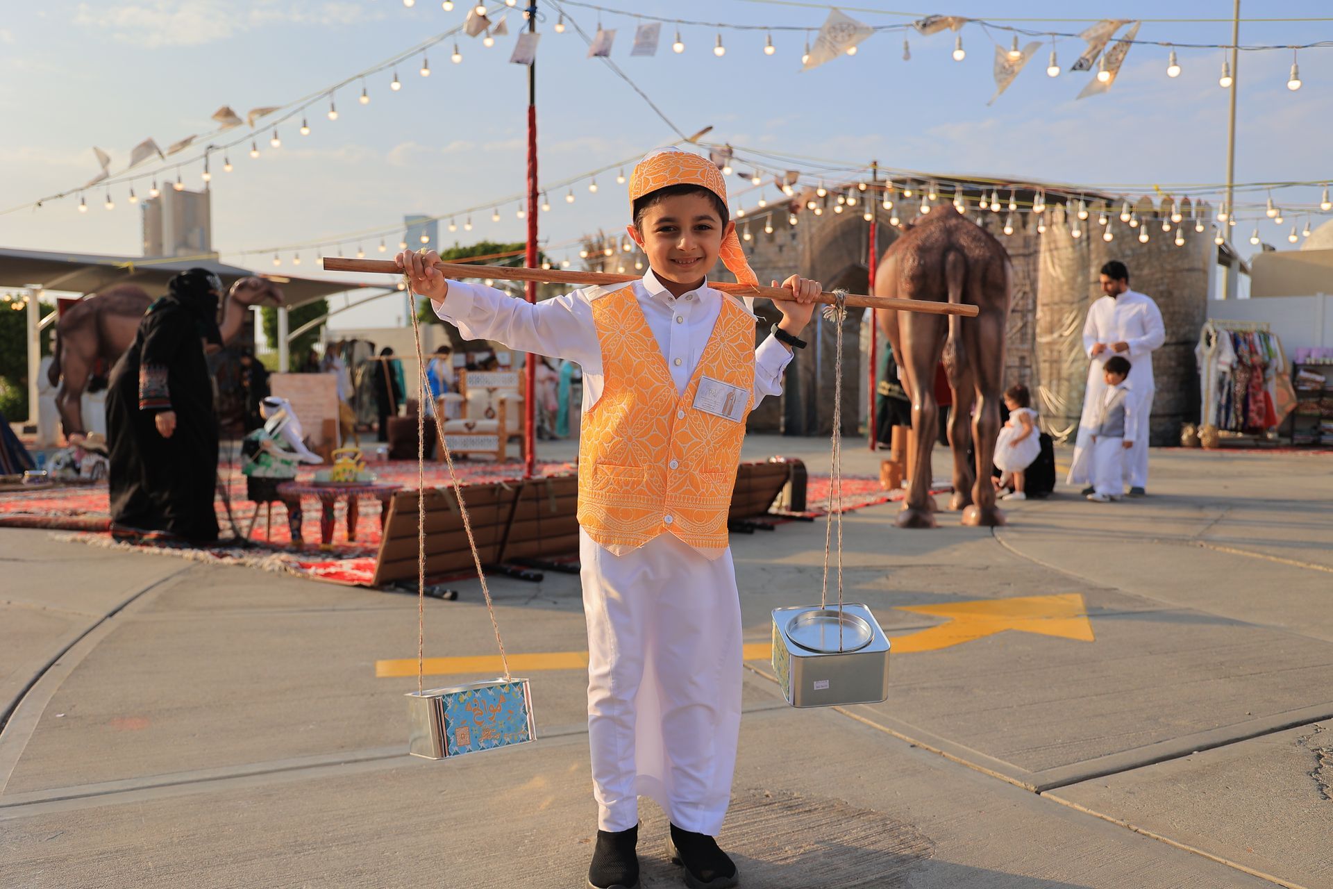 A young boy is holding a stick in front of a camel.