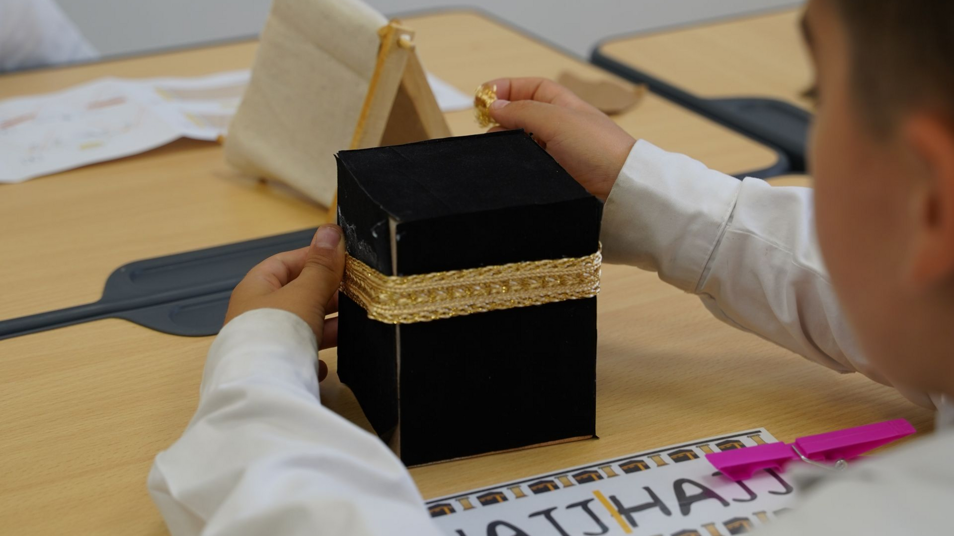Student making a Kaaba model for a Hajj craft project at Roya International School in Jeddah