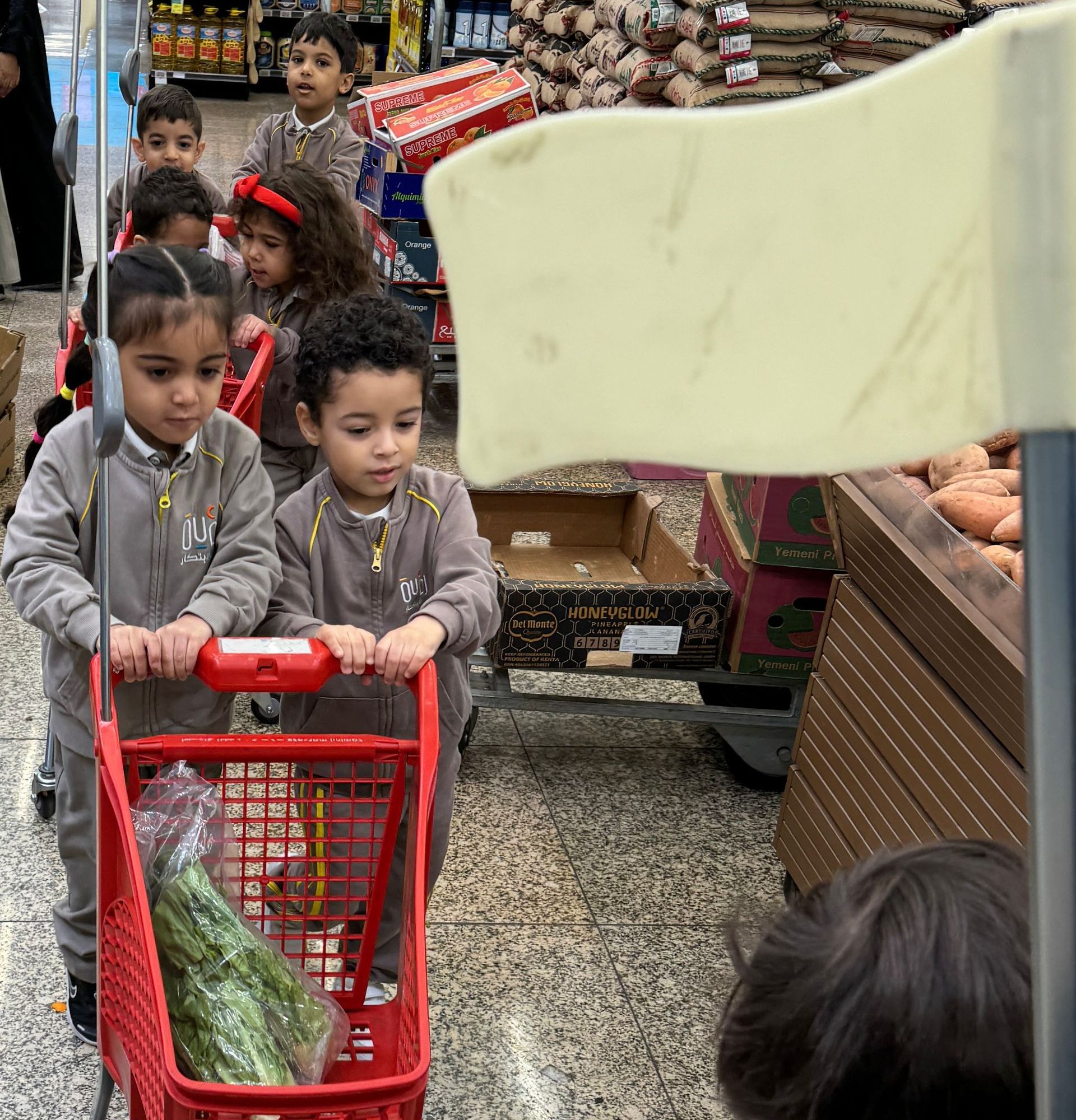 A group of children are pushing a shopping cart in a grocery store.