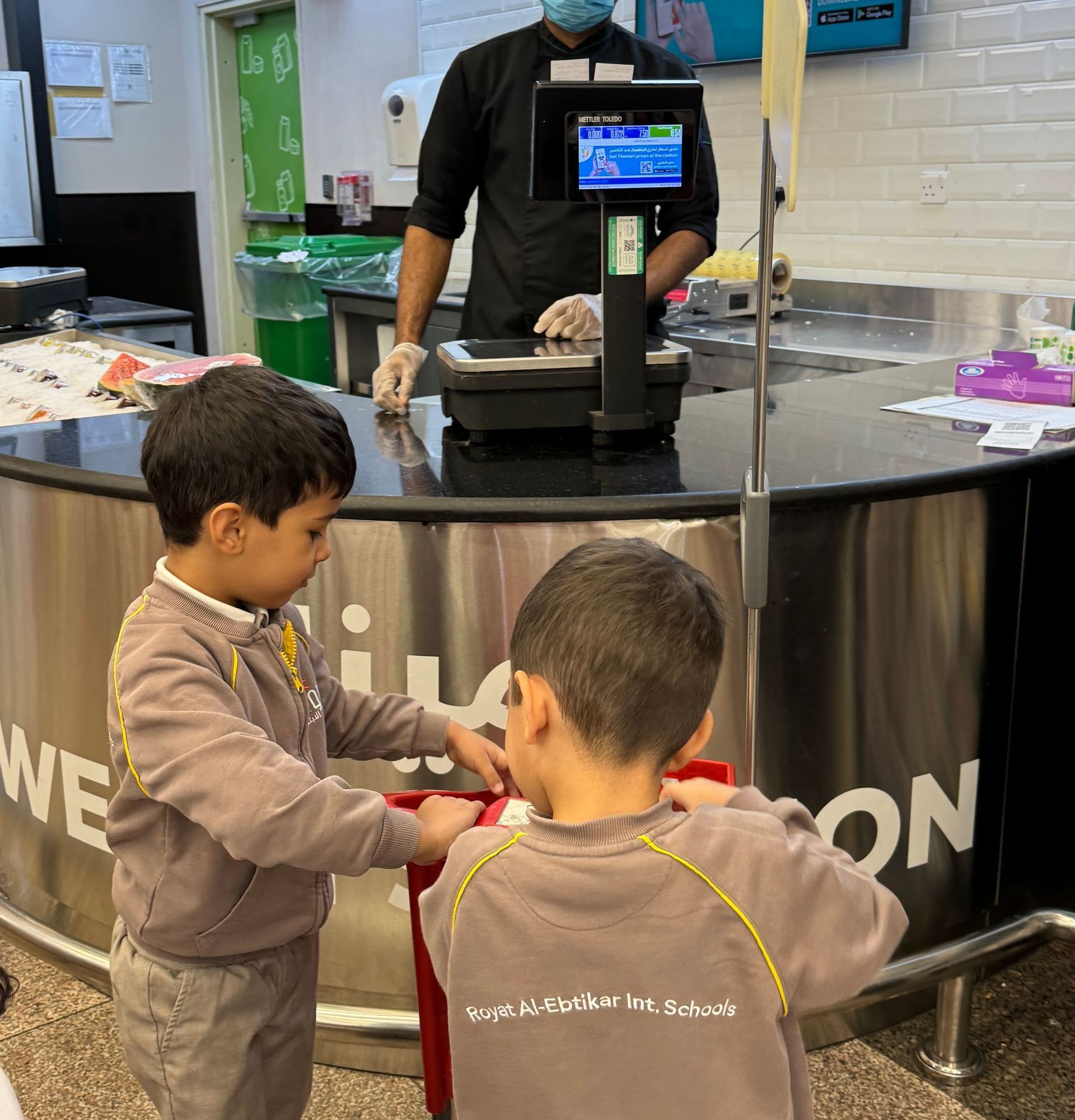 Two young boys are standing in front of a counter in a restaurant.
