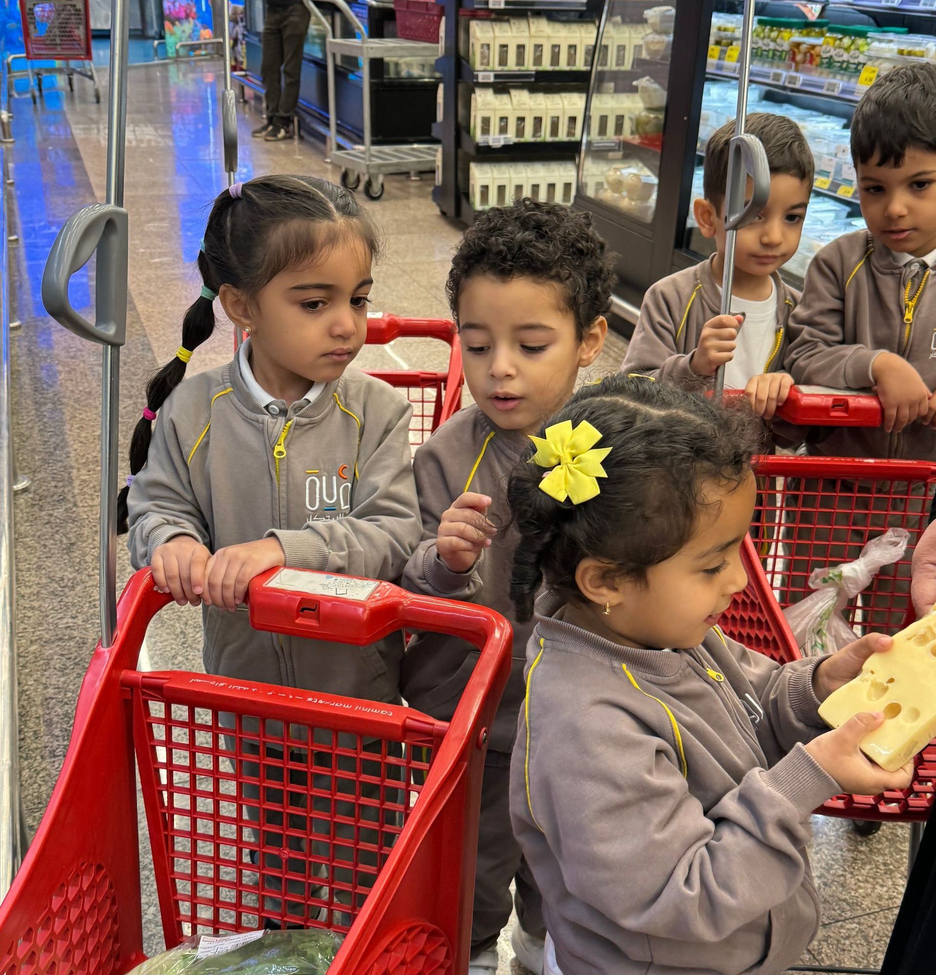 A group of children are pushing shopping carts in a grocery store.